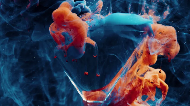 Orange and blue ink swirling in a glass